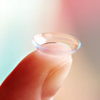 A patient holding a contact lens on the tip of their finger before applying it to their eye