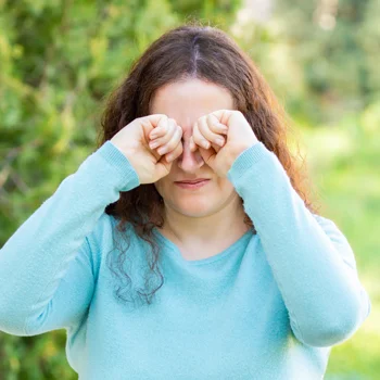 Eye Doctor Plainfield IL Dry Eye BOX A young woman walking outside, rubbing her itchy, dry eyes