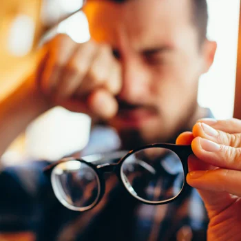 Eye Doctor Plainfield IL Myopia Management A man removing his glasses to rub at his eyes, feeling eye strain