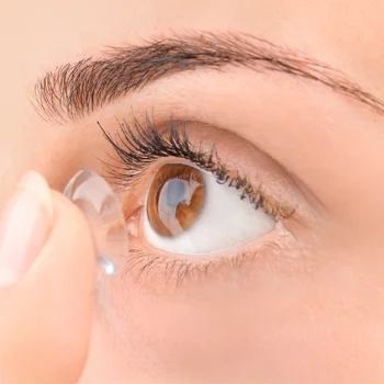 A contacts user looking upward as she applies the lens to her eye